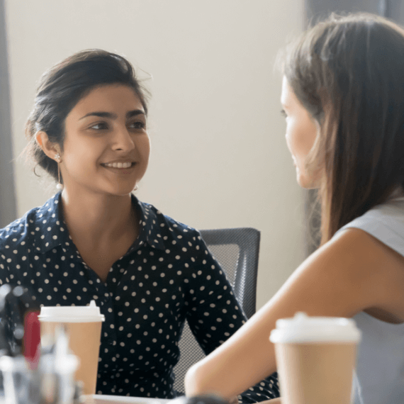 Two woman talking with a cup of coffee